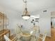 Dining area with decorative chandelier and glass table that flows into the white kitchen at 426 Bouchelle Dr # 202, New Smyrna Beach, FL 32169