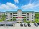 Beige four-story condo building with a green roof, parking, and tropical landscaping at 426 Bouchelle Dr # 202, New Smyrna Beach, FL 32169