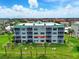 Rear exterior view of condo with screened in lanai, green lawn, and palm trees at 426 Bouchelle Dr # 202, New Smyrna Beach, FL 32169