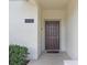 Close-up of the home's entryway shows a solid brown door, address number, and manicured landscaping at 4895 Clock Tower Dr, Kissimmee, FL 34746