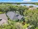 Aerial view of home surrounded by trees and a lake in the background at 5263 Beach River Road, Windermere, FL 34786