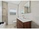 Bathroom features a modern vanity with wood accents, neutral tile, and a large mirror at 5521 Makoma Dr, Orlando, FL 32839