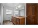 Bathroom with long vanity and sink, a toilet, a window, wood-look floors and a wooden door at 5891 Sir Henry Rd, Orlando, FL 32808