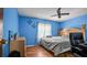 Bedroom with blue walls, wood floors, a ceiling fan, curtains on the window, and wood furniture at 5891 Sir Henry Rd, Orlando, FL 32808