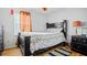 Bedroom with wood floors, black bed frame, patterned bedspread, and a nightstand with a lamp at 5891 Sir Henry Rd, Orlando, FL 32808