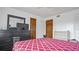 Bedroom with red and white patterned bedspread, black dresser with mirror, and two wooden doors at 5891 Sir Henry Rd, Orlando, FL 32808