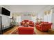 Cozy living room with bright orange sofas, a glass coffee table, and a mounted television at 5891 Sir Henry Rd, Orlando, FL 32808