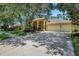 Inviting yellow home featuring a three-car garage, manicured lawn, mature trees, and a covered front entry at 6092 Sabal Hammock Cir, Port Orange, FL 32128