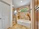 Bright bathroom with tiled floors, shower, soaking tub, and arched window at 6630 Hidden Beach Cir, Orlando, FL 32819