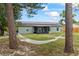 Large backyard view with a hammock, mature trees and a glimpse of the house with its solar panels and screened porch at 705 Ibis Ave, Deltona, FL 32738