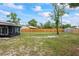 Expansive backyard with a new fence, mature trees, and lush green lawn with a glimpse of the exterior of the house at 705 Ibis Ave, Deltona, FL 32738