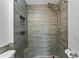 Modern walk-in shower boasts wood-look tile, a rainfall showerhead, a handheld sprayer, and a convenient built-in niche at 705 Ibis Ave, Deltona, FL 32738