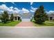 Charming blue single-Gathering home showcasing a brick driveway, lush landscaping, and an attached two-car garage at 7530 Summerlake Groves St, Winter Garden, FL 34787