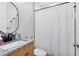 Modern bathroom featuring a granite vanity countertop, a sleek oval mirror, and a bright white shower curtain at 8290 Nemours Pkwy, Orlando, FL 32827