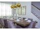 The dining room is set for dinner with a view of the staircase and features elegant chandeliers at 9071 Sunshine Ridge Loop, Kissimmee, FL 34747