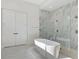 Bright bathroom features soaking tub and glass-enclosed shower with marble tile at 9156 Sheen Sound St, Orlando, FL 32836