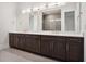 Bathroom with dual sinks, dark wood cabinets, white countertops, modern lighting and a tiled shower at 9156 Sheen Sound St, Orlando, FL 32836