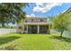 Expansive green backyard featuring a screened-in porch connected to a two-story home under a partly cloudy blue sky at 10142 Serotina Ct, Orlando, FL 32832