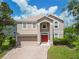 Charming two-story home with red door, beige exterior, manicured lawn and brick driveway at 10142 Serotina Ct, Orlando, FL 32832