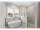 Bright bathroom with free-standing tub, marble tile, and walk-in shower with glass door at 102 Hammock Preserve Loop, Winter Garden, FL 34787