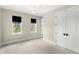 Bright bedroom with plush carpet, two windows with black shades, and a modern ceiling fan at 102 Hammock Preserve Loop, Winter Garden, FL 34787