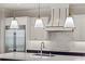 Well-equipped kitchen featuring stainless steel refrigerator, stylish range hood, sleek countertop and designer pendant lights at 102 Hammock Preserve Loop, Winter Garden, FL 34787