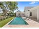 Backyard pool featuring a travertine patio and a tranquil setting with lush landscaping and privacy fencing at 102 Hammock Preserve Loop, Winter Garden, FL 34787
