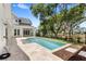 Backyard pool featuring a travertine patio and a tranquil setting with lush landscaping, perfect for relaxation at 102 Hammock Preserve Loop, Winter Garden, FL 34787