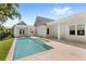Backyard pool featuring a travertine patio and a tranquil setting with lush landscaping and white exterior at 102 Hammock Preserve Loop, Winter Garden, FL 34787