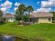 Well-maintained backyard featuring a covered patio, lush lawn, and tropical landscaping near a pond at 106 Winghurst Blvd, Orlando, FL 32828