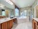 Bright bathroom features a large garden tub, glass enclosed shower, double vanity, and decorative wallpaper at 106 Winghurst Blvd, Orlando, FL 32828