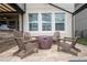 Back patio area with paver stones, a built-in gas fire pit surrounded by four Adirondack chairs, with windows in the background at 1097 Trappers Trail Loop, Davenport, FL 33896