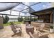 This screened patio has a hot tub, outdoor kitchen and dining space with a fire pit surrounded by Adirondack chairs at 1097 Trappers Trail Loop, Davenport, FL 33896