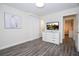 Bright bedroom features grey wood floors, white dresser, and TV with an outdoor scene at 1097 Trappers Trail Loop, Davenport, FL 33896