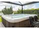 Covered back patio with a built-in hot tub with jets, overlooking the lake surrounded by evergreen trees at 1097 Trappers Trail Loop, Davenport, FL 33896