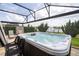 The back patio has a built-in hot tub with jets, overlooking the lake, with lounge chairs and black metal chairs at 1097 Trappers Trail Loop, Davenport, FL 33896