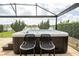 Covered back patio with a built-in hot tub with jets and black metal chairs, overlooking the lake at 1097 Trappers Trail Loop, Davenport, FL 33896