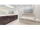 Modern bathroom features a soaking tub, glass shower, and dual sink vanity with dark wood cabinets at 14124 Dove Hollow Dr, Orlando, FL 32824