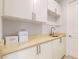 Bright laundry room with a sink, white cabinetry, and a neutral countertop at 14124 Dove Hollow Dr, Orlando, FL 32824