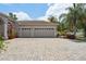 Side view showing a three-car garage with a brick driveway and well-maintained landscaping at 1542 Wescott Loop, Winter Springs, FL 32708