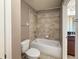 Bathroom with shower-tub combo, neutral tiling, and a white toilet at 1546 Water Elm Ct, Orlando, FL 32825