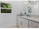 Bathroom with a granite countertop, white cabinets, and a window that provides natural light and a view of the outdoors at 167 S Sheridan Ave, Deland, FL 32720