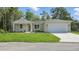 View of the home's facade, featuring a wide lawn, driveway, and attached garage at 17 Cypress Run, Haines City, FL 33844