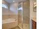 Bright bathroom featuring a glass shower, large bathtub, and neutral floor tiling at 17322 Chateau Pine Way, Clermont, FL 34711