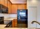 Modern kitchen featuring wooden cabinets, sleek black appliances, and light countertops at 17322 Chateau Pine Way, Clermont, FL 34711