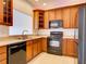 Kitchen featuring wood cabinets, black appliances, and tile floors for easy maintenance at 17322 Chateau Pine Way, Clermont, FL 34711