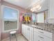 Bright bathroom featuring a granite countertop, white cabinetry, and a window with beach views at 2121 Hill St # 7B, New Smyrna Beach, FL 32169