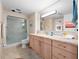 Bathroom with glass-enclosed shower, large mirror, and tan marble countertops at 2121 Hill St # 7B, New Smyrna Beach, FL 32169