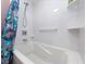 A close-up view of a bathtub with white tiles and a shower head at 2121 Hill St # 7B, New Smyrna Beach, FL 32169