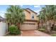 Stunning two-story home featuring a brick driveway, two-car garage, and beautiful palm trees at 2121 Morocco Way, Kissimmee, FL 34747